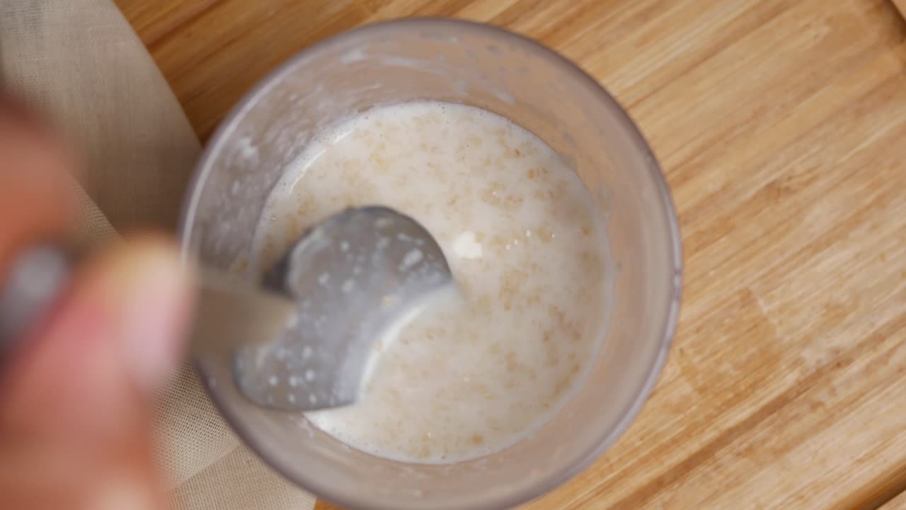 Avena, banana e latte in una ciotola su sfondo nero.