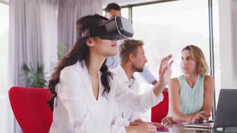 professional businesswoman using virtual reality headset while sitting in office in slow motion