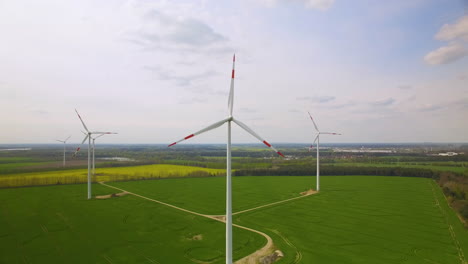 aerial view of windmills in a big green cultivated land for agriculture, sunny blue sky with clouds