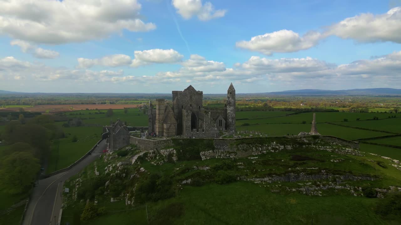 4K Aerial view of the Rock of Cashel, capturing ancient stone walls, round towers, and cathedral ruins surrounded by rolling green fields and historic farmland. Co.Tipperary, Ireland_014