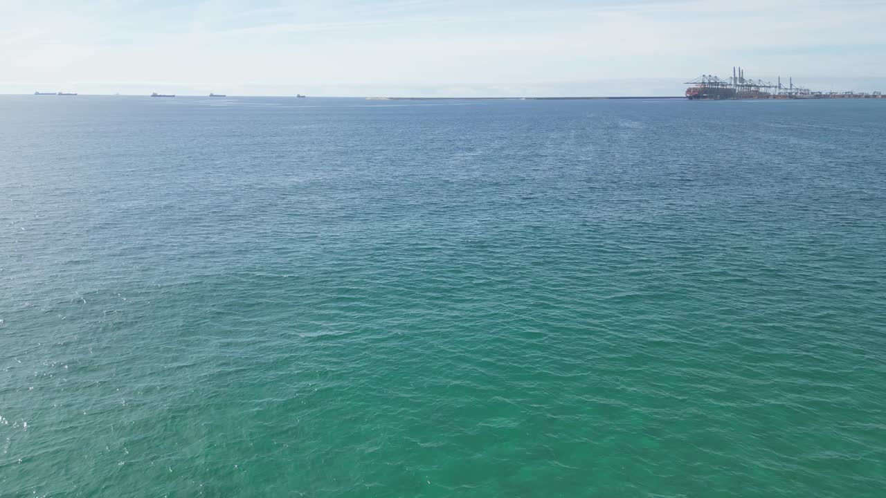 Wide view of calm turquoise sea near Sines port, Portugal, under clear blue sky