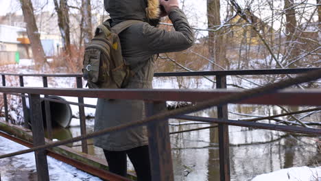 donna che scatta foto mentre cammina nella natura innevata.