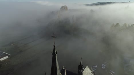 blissful morning with stunning mist in valley with breathtaking church, aerial