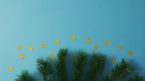 fir tree branches with stars and copy space on blue background