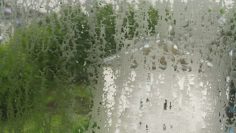 drops of water, like lenses, on mosquito net. summer pouring rain in city. 4k video