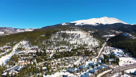 aerial drone view: breckenridge, colorado rocky mountains on a sunny day with snow-covered forest and peak