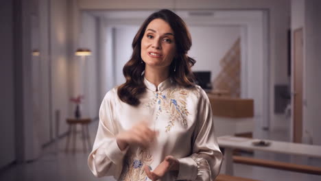 A woman smiling and gesturing in a modern indoor setting