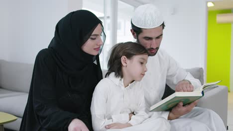 muslim family reading quran and praying together on the sofa
