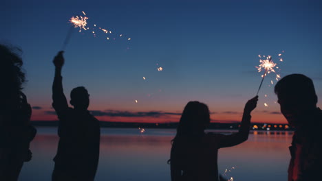 friends celebrating at sunset by the lake with sparkler