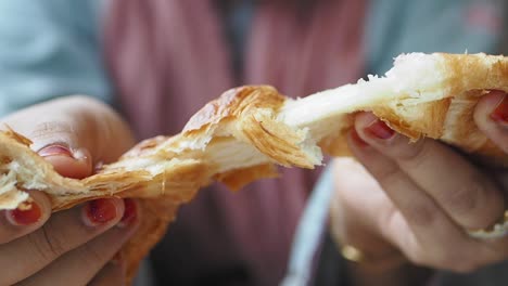 una mujer comiendo un croissant.