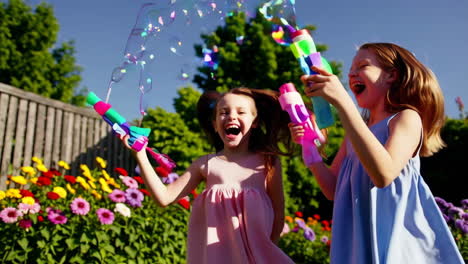happy girls playing with bubble guns in a sunny garden