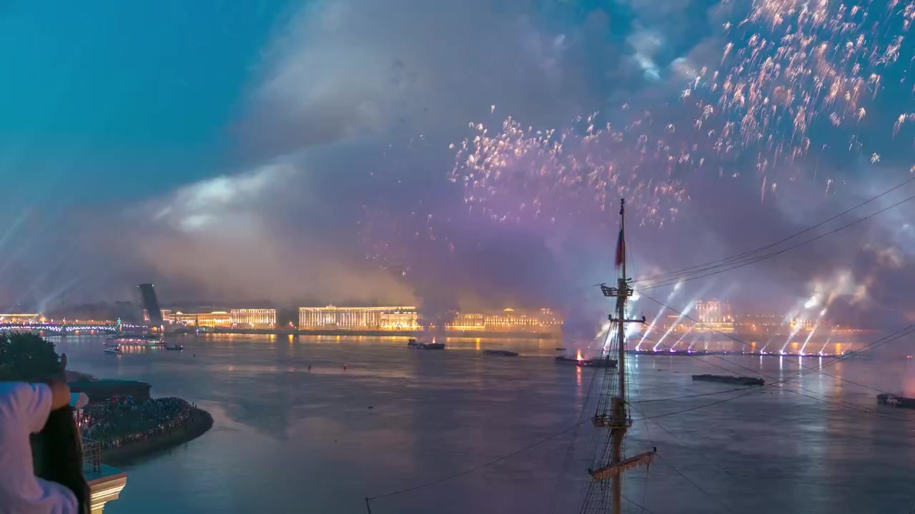 Feuerwerk im Zeitraffer über der Stadt St. Petersburg (Russland) am Fest der Scharlachroten Segel, Blick vom Dach. Blick auf die Dreifaltigkeitsbrücke.
