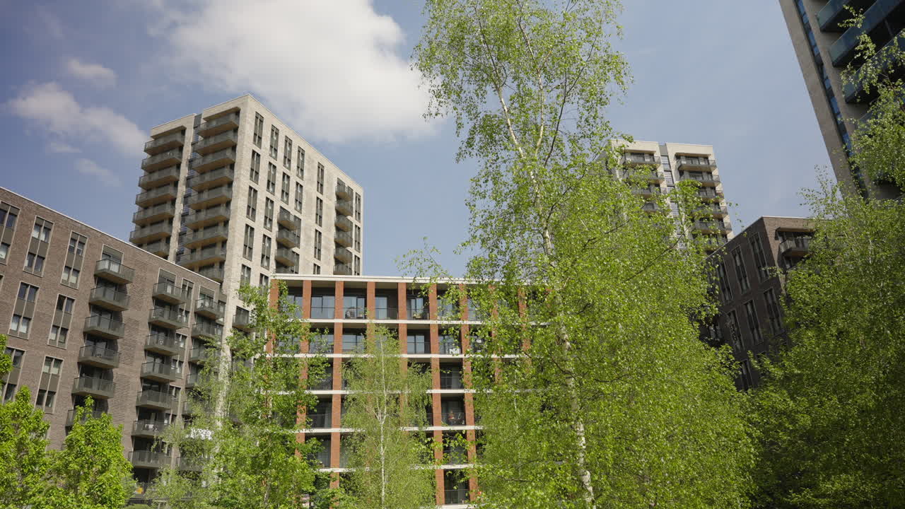 Modern residential towers in Wembley, London, with trees in foreground blending urban with greenery