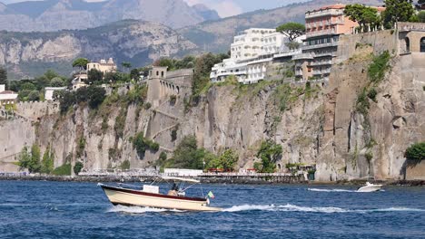 a boat travels near cliffs and buildings