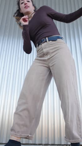 young woman dancing freestyle in front of metal wall