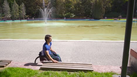 Disabled-young-man-sitting-on-bench-from-wheelchair.