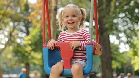 adorable toddler girl happily swinging in a sunny playground