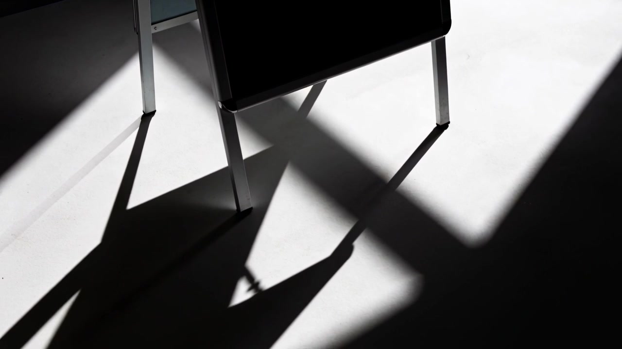 Shifting sun causing metal chair casting sliding long shadows layering on floor in studio, window