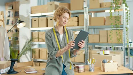 young caucasian designer woman typing on tablet at office in clothing shop