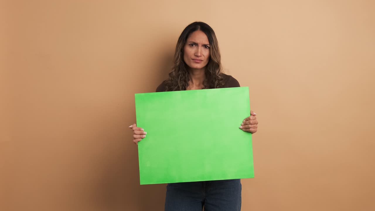 Woman holding a blank green panel and gesturing negatively