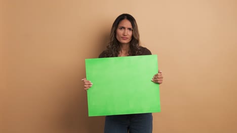 woman holding a blank green panel and gesturing negatively