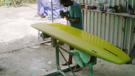 high angle gimbal shot of shaper painting surfboard