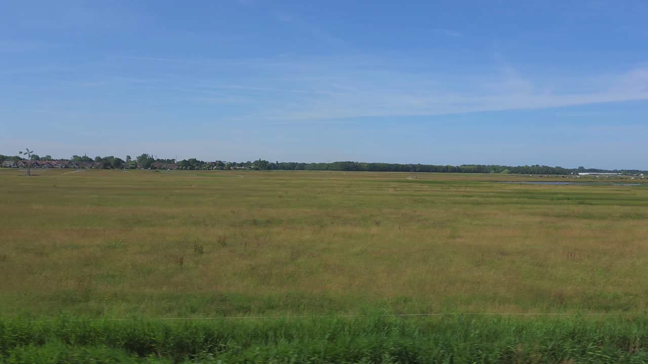 View of the Dutch countryside on a sunny day from a moving train
