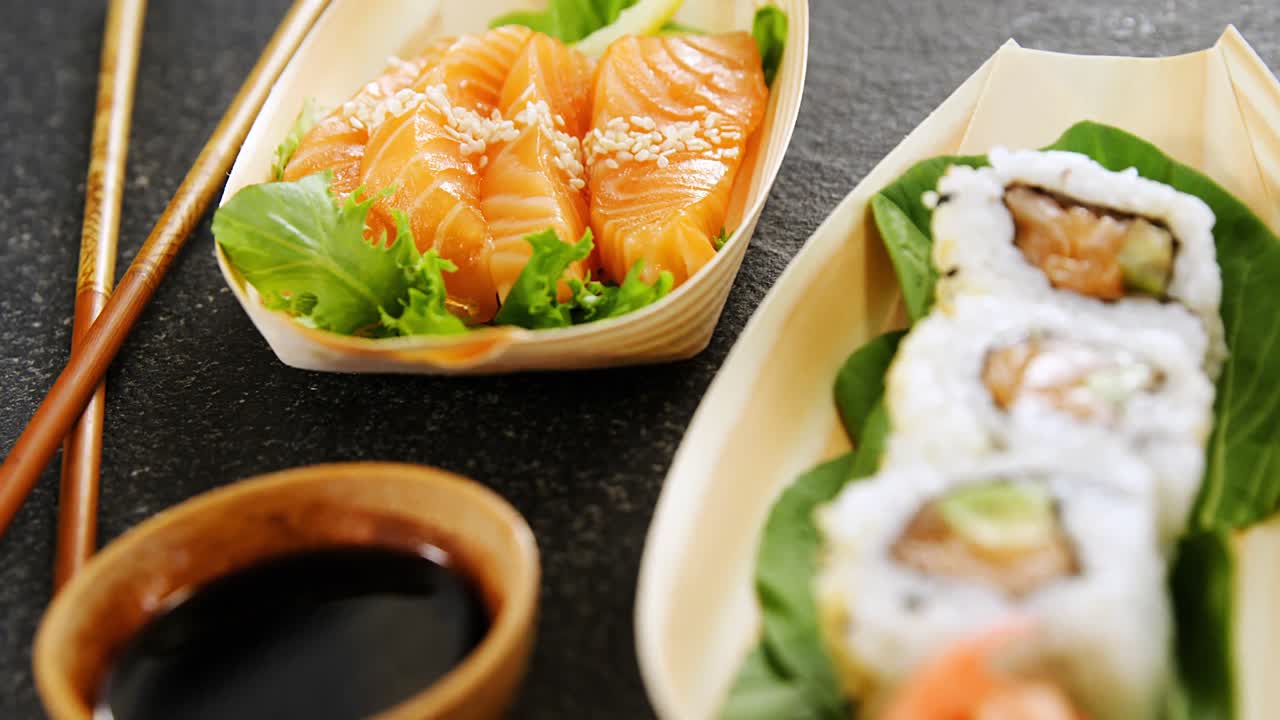Sushi sul piatto a forma di barca con le bacchette