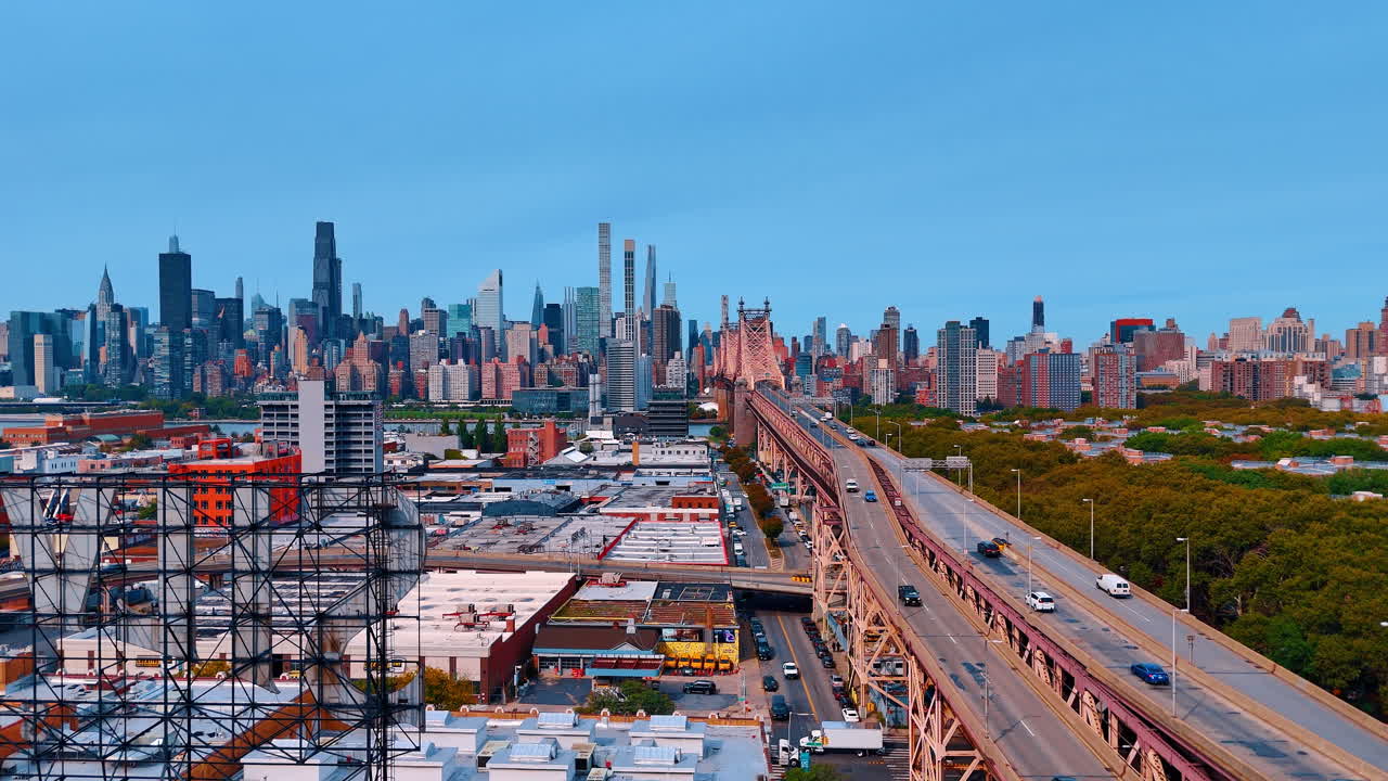 Un grande ponte a sbalzo che collega aree urbane sopra un fiume, conducendo allo skyline della città e offrendo una vista sullo skyline e su un parco verde al tramonto.