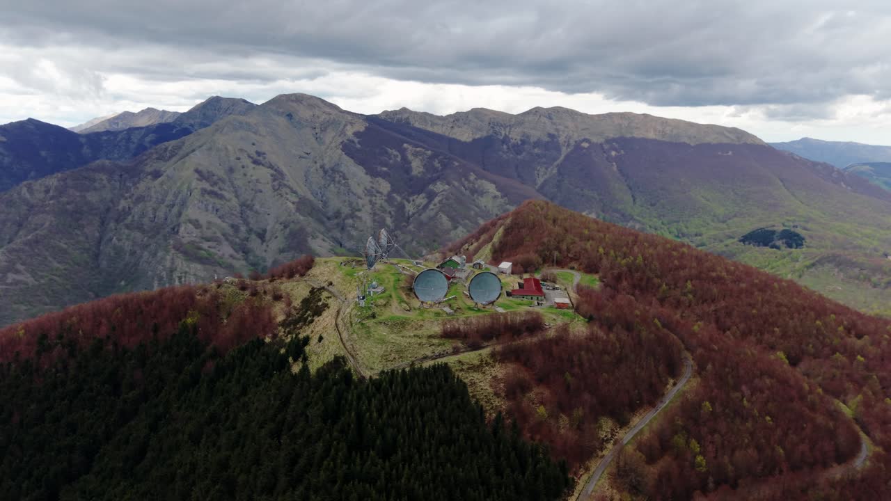 Old radar station on mountain peak under cloudy sky, remote and dramatic view