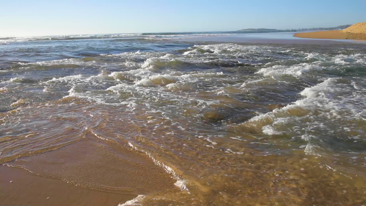 POV from within the surf being buffeted around within the waves surrounded by sand and bubbles and wave froth