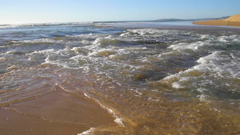 punto de vista desde dentro de las olas siendo azotado dentro de las olas rodeado de arena y burbujas y espuma de olas
