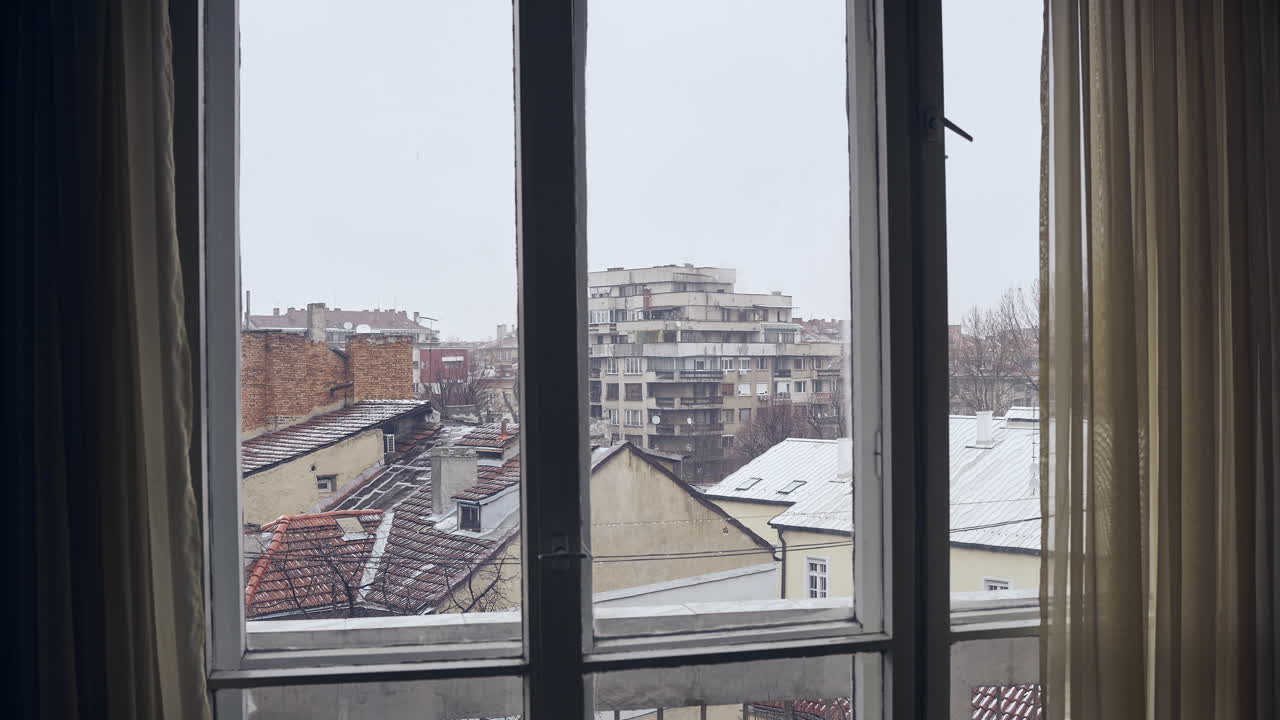 un lapso de tiempo de 4k a través de una ventana de un día nevado de invierno en sofía, bulgaria, en la unión europea