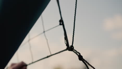 close-up of volleyball net being held by someone checking its firmness with a hazy sky in the background during an outdoor training session