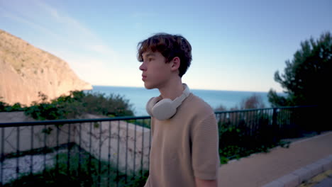 teenager walking along coastal path with headphones