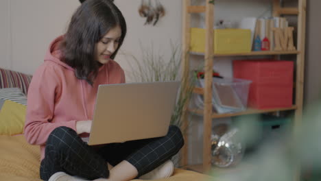 teenage girl working on laptop in her bedroom