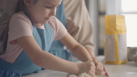 una niña pequeña y su madre están amassando masa en la cocina de la casa cocinando y horneando pan doméstico