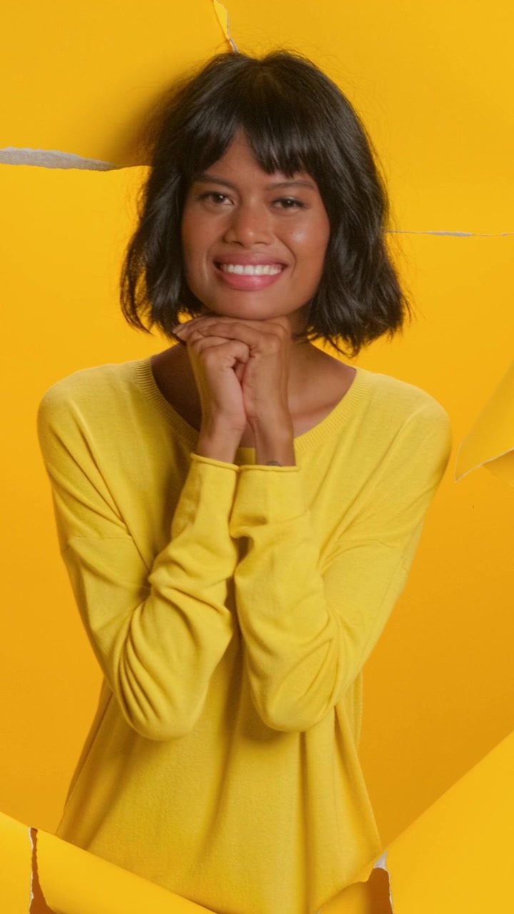 Ritratto di una donna sorridente con un maglione giallo su uno sfondo giallo brillante