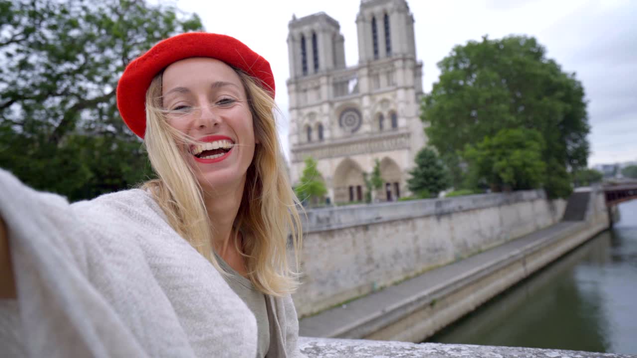 mujer joven de 4k tomando una selfie en parís en la ciudad de notre dame usando un teléfono móvil