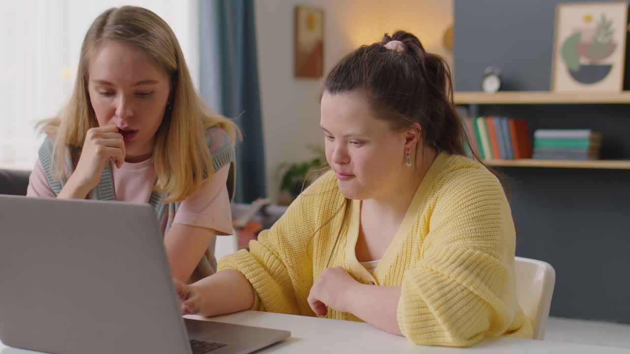 Ragazza con sindrome di Down che usa un laptop con l'insegnante durante una lezione a casa