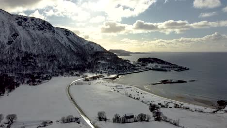 A breathtaking aerial view of pristine Arctic winter scenery, showcasing the majesteic highway of Northern Norway with snow covered beach and a stuning ocean in 4k.