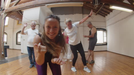 Tracking-shot-of-young-female-teacher-dancing-in-ballroom-with-her-students