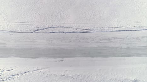 a utility terrain vehicle races past an overhead camera on an icy road