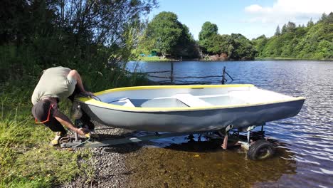 man preparing to launch compact fiberglass boat from trailer into lake