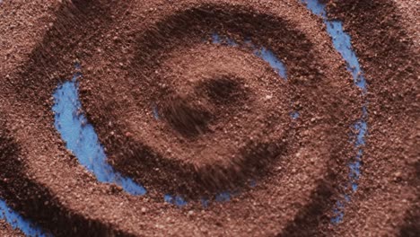 Video-of-close-up-of-brown-sand-grains-and-copy-space-in-swirl-on-blue-background