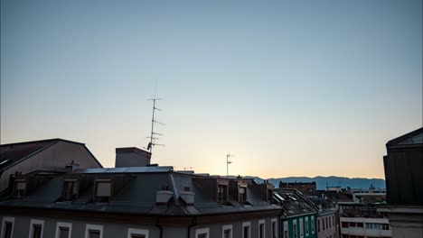bright white sun and beam above buildings in blue sky with clouds by distant mountain range at sunset, time lapse day to night