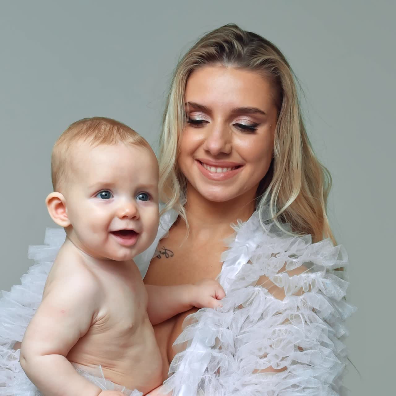 Retrato de m\[atilde]e e filho. Mulher loira segura seu pequeno menino de olhos cinzas, sorrindo para a c\[acirc]mera. Tela vertical