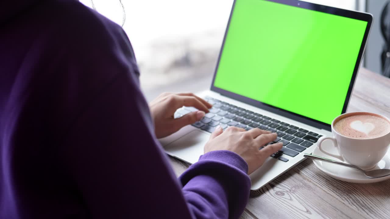 Woman using laptop notebook viewing green screen press browsing chroma key online typing text working remotely on laptop computer close up hands in cafe