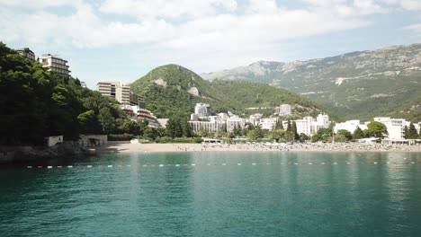 drone-fly-above-Adriatic-Sea-water-in-scenic-coastline-near-Bečići-town-in-the-municipality-of-Budva,-Montenegro-resort-beach-town