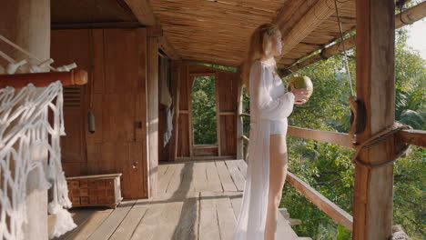 hermosa mujer bebiendo cóctel de coco en el balcón con vista al bosque tropical disfrutando del estilo de vida de vacaciones en un complejo hotelero exótico